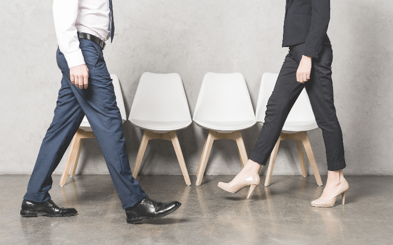 Two people walking past each other in office attire