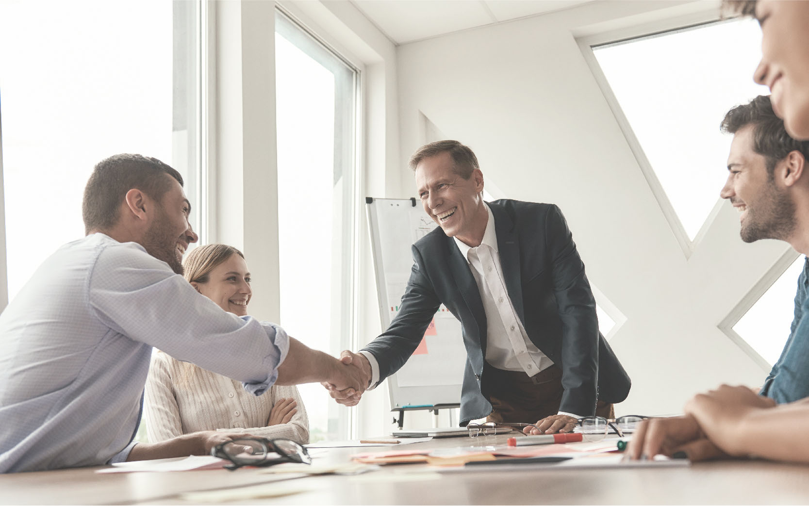 Two men shaking hands at table of people